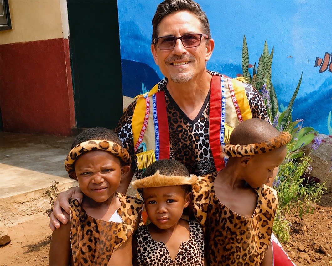 Randy Finkbeiner in traditional dress with three Zonke Izizwe children