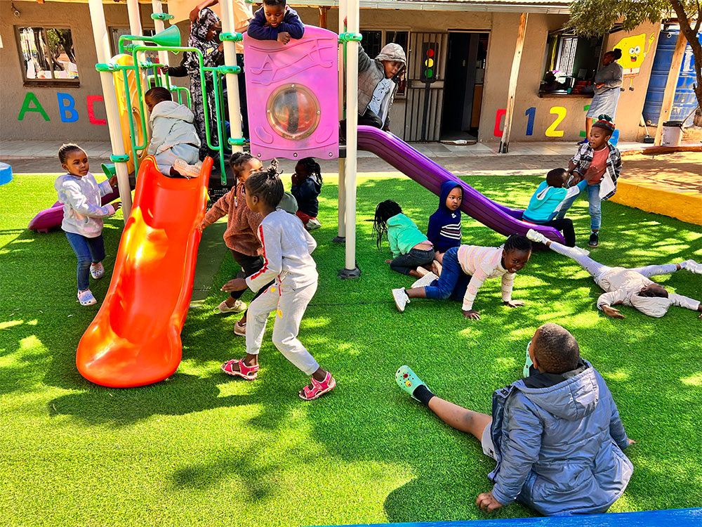Children playing on the playground equipment on the artificial grass
